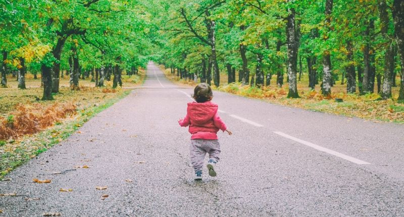 Un niño pequeño caminando por la carretera