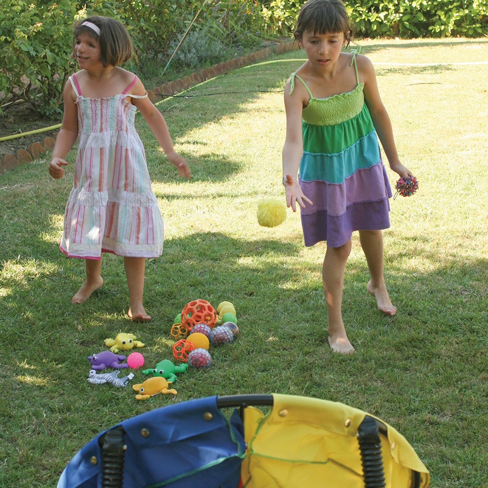 Dos niñas jugando a tirar pelotas a un blanco.