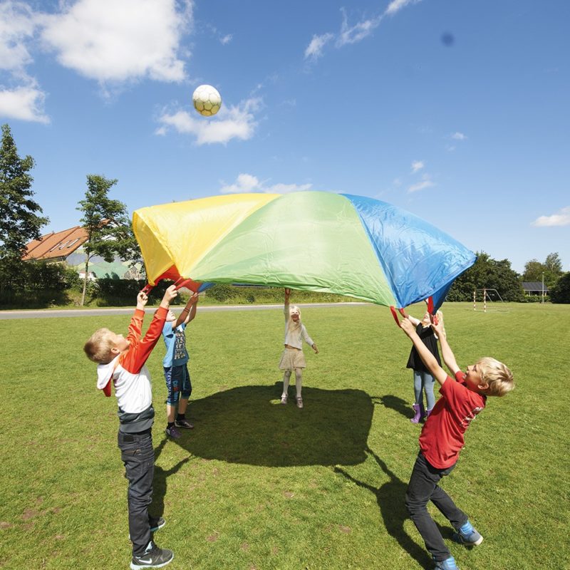 Niños jugando al juego del paracaídas.