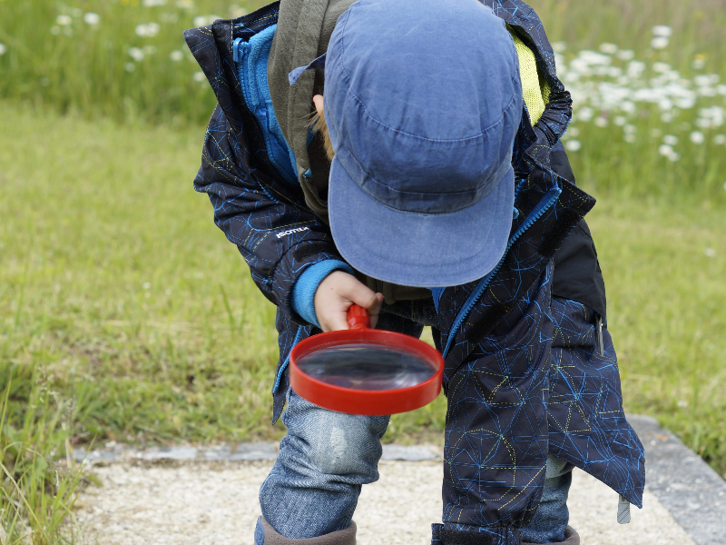 Un niño juega con una lupa al aire libre