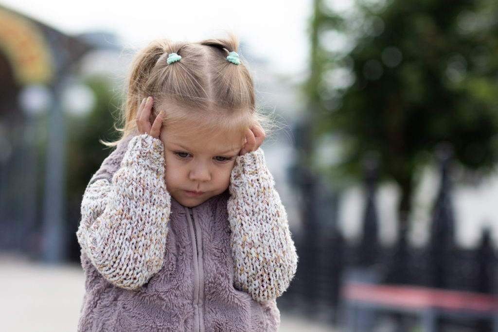 Niña hipersensible que se sujeta la cabeza con las manos