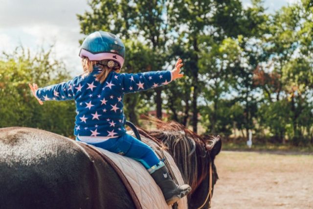 una niña pequeña montando a caballo