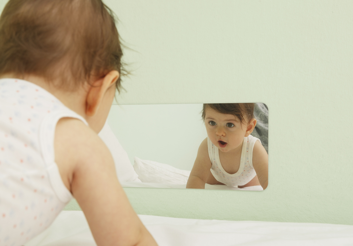Un bebé se mira en un espejo