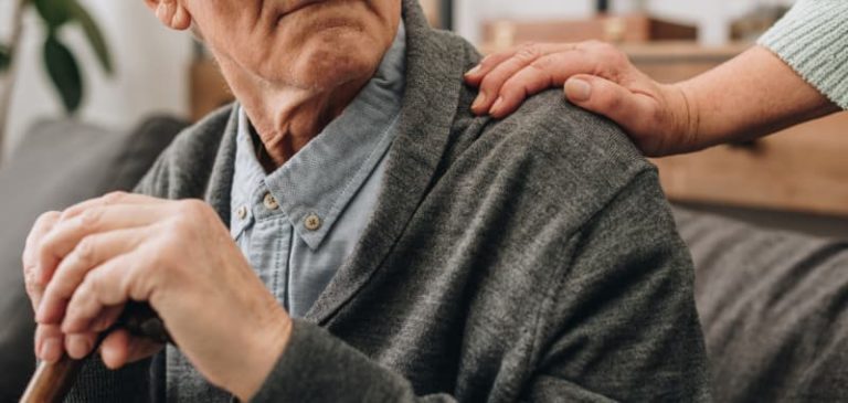 un anciano sentado con un bastón en una residencia